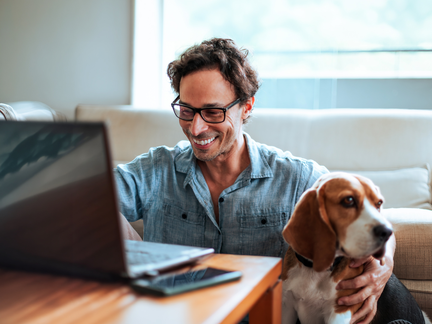 Man working on his laptop at home, while petting his wonderful dog.